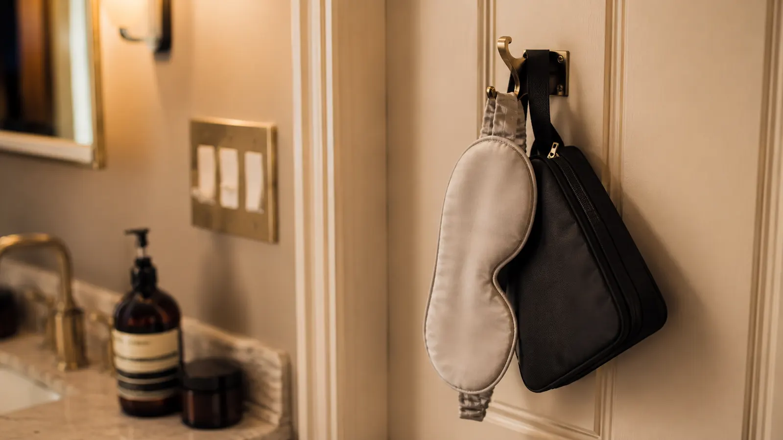Sleep mask hanging on a bathroom hook next to a travel toiletry bag, showing portability for travel