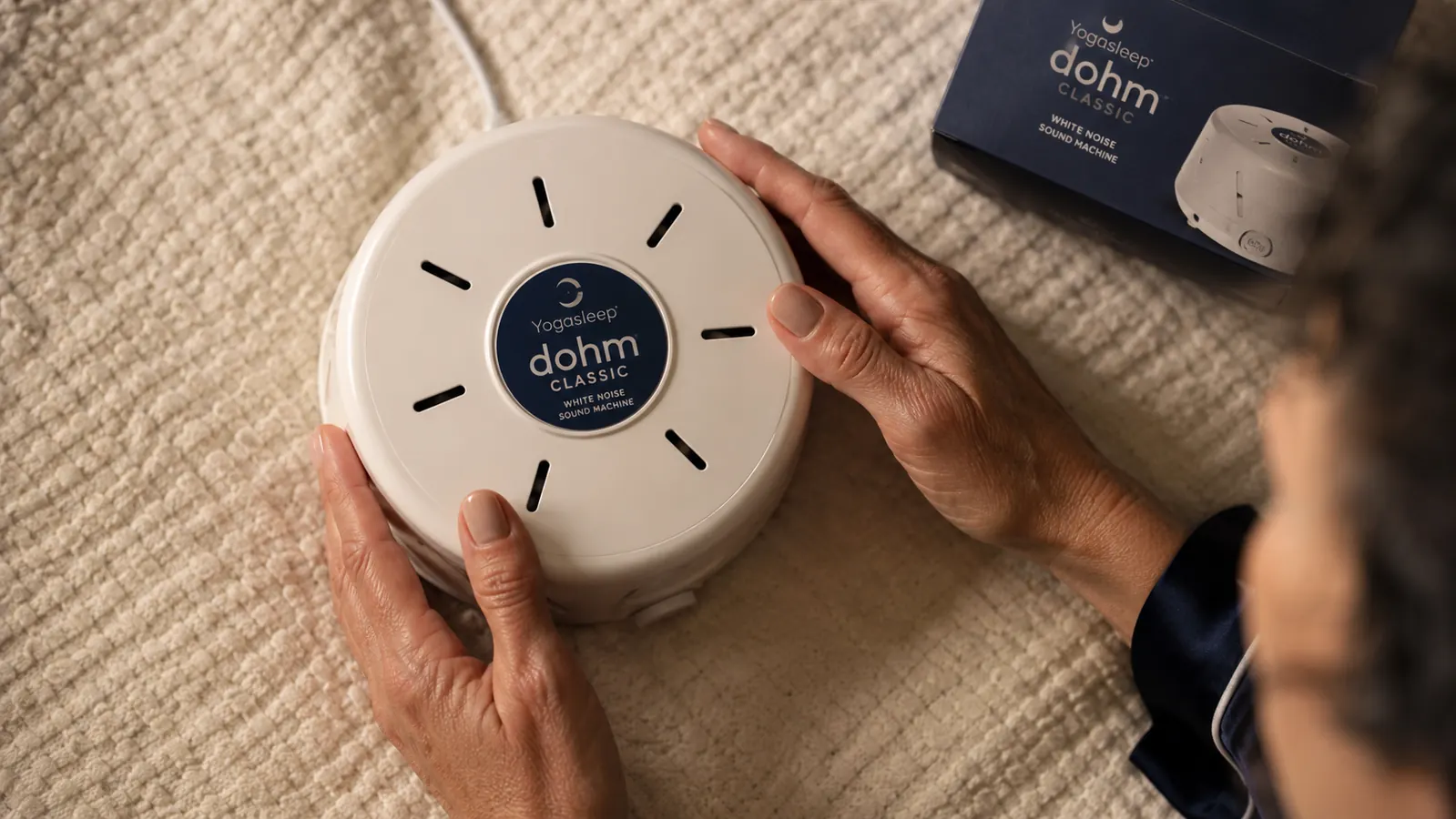 Top-down view of a Yogasleep Dohm Classic with the volume dial visible, sitting on a cream-colored surface